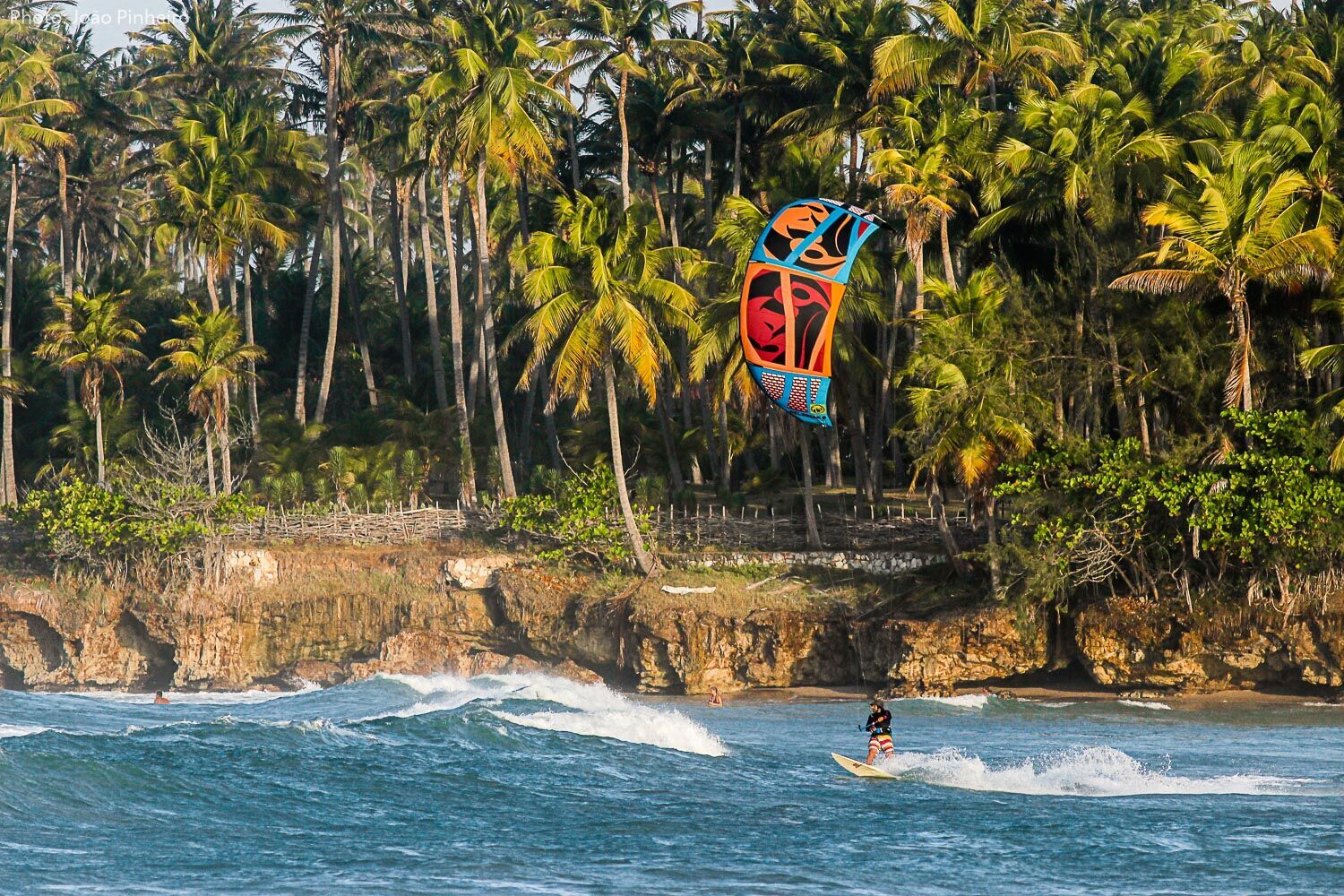 http://Kitesurfeur%20naviguant%20sur%20les%20vagues%20le%20long%20d'une%20plage%20tropicale%20bordée%20de%20cocotiers%20et%20de%20falaises%20au%20Nordeste%20du%20Brésil.