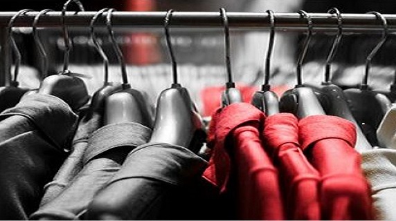 Gros plan sur des cintres avec des veste de costume sur une penderie.