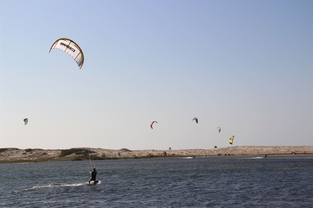 http://Kitesurfeurs%20naviguant%20sur%20une%20lagune%20d'eau%20calme%20avec%20un%20panorama%20de%20dunes%20de%20sable%20sous%20un%20ciel%20dégagé%20au%20Nordeste%20du%20Brésil.