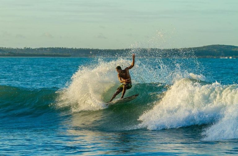 Un surfeur réalise un virage dynamique sur une vague dans l'océan turquoise lors de voyages sportifs et aventures au Brésil.