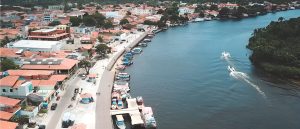 Vue aérienne de Barreirinhas au Maranhão avec le fleuve Preguiças, ses bateaux amarrés le long des quais et deux vedettes naviguant sur l'eau.