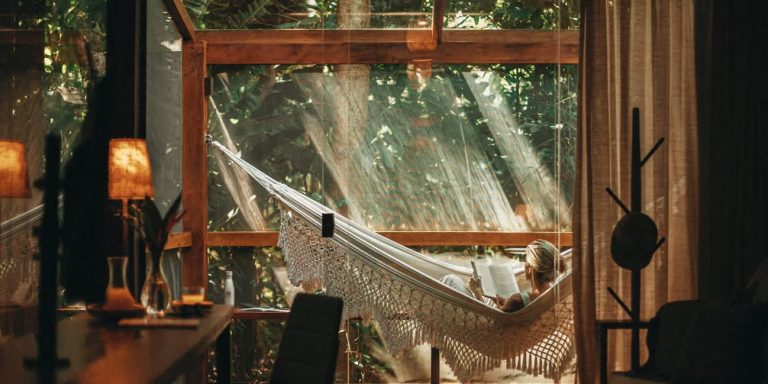 Coin lecture et hammac haut de gamme sur la véranda vitrée d'un chalet de luxe avec vue sur la forêt amazonienne.