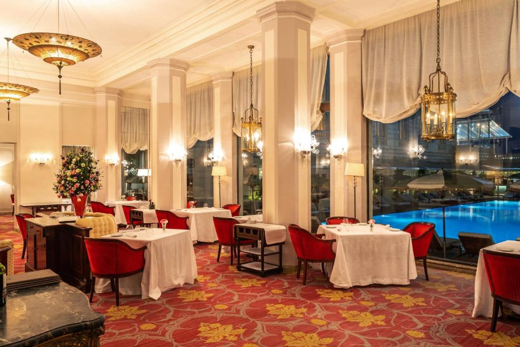 Salle de restaurant de luxe du Copacabana Palace avec tables dressées, moquette rouge et grandes baies vitrées donnant sur la piscine.