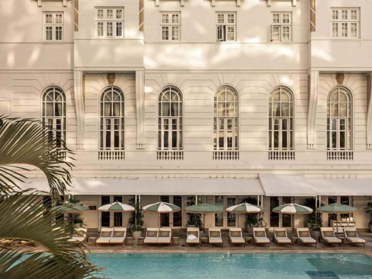 Façade néoclassique blanche et piscine emblématique de l'hôtel Copacabana Palace à Rio de Janeiro.