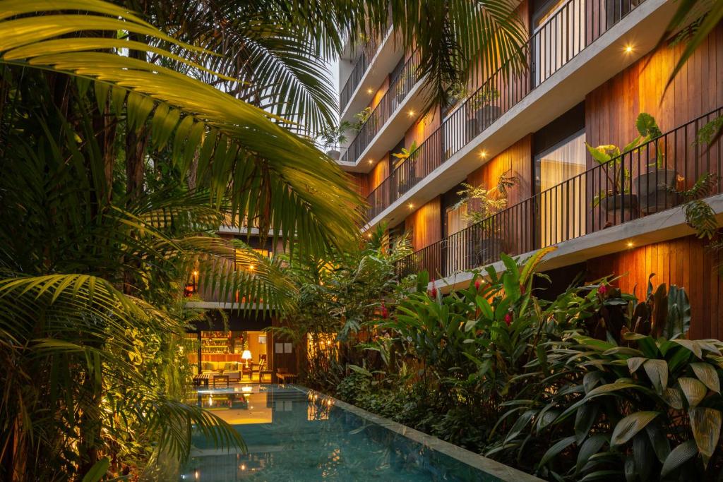 Jardin tropical verdoyant et piscine reflétant les balcons éclairés de l'hôtel boutique Vila Amazônia à Manaus.